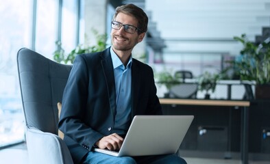 Businessman using laptop computer in office. Happy man, entrepreneur, small business owner working...