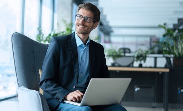 Fototapeta Businessman using laptop computer in office. Happy man, entrepreneur, small business owner working online.