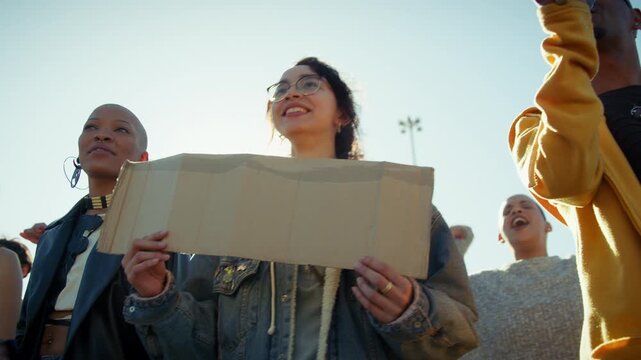 Group of young activists engage in a public protest, holding signs and using a megaphone. They advocate for change and express their collective voice in an outdoor rally.