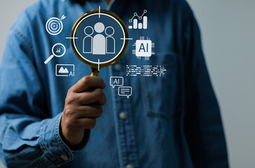 Businessman holding magnifying glass with AI icons target audience analytics, Concept of artificial intelligence, marketing data analysis, and digital customer insight strategy