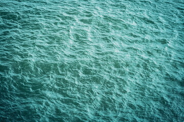 Green or turquoise ocean water surface aerial view. Top down view, calm ocean waters and ripples, no people