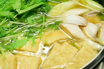 A stewed hot pot dish featuring mizuna greens, green onions, mackerel, and fried tofu—a Japanese winter delicacy.