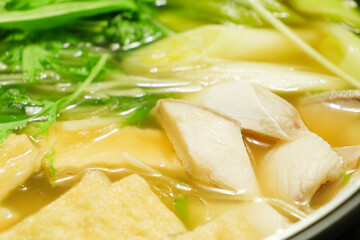 A stewed hot pot dish featuring mizuna greens, green onions, mackerel, and fried tofu—a Japanese winter delicacy.
