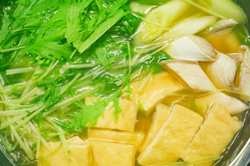 A stewed hot pot dish featuring mizuna greens, green onions, mackerel, and fried tofu—a Japanese winter delicacy.