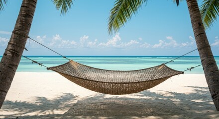Woven fiber resting net suspended between tropical palm trunks leaning over a brilliant white sandy coast during a sunny summer vacation day ,tranquil ,white ,shore