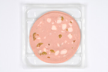 An overhead shot of a package containing several round slices of mortadella with visible olives and fat pieces, centered on a white background