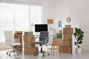 Moving day. Cardboard boxes, computer and furniture in office