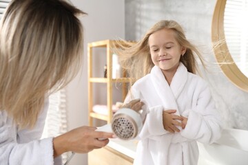 Woman blow drying her daughter's hair in bathroom