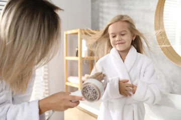 Fotobehang Muziek Woman blow drying her daughter's hair in bathroom  © New Africa