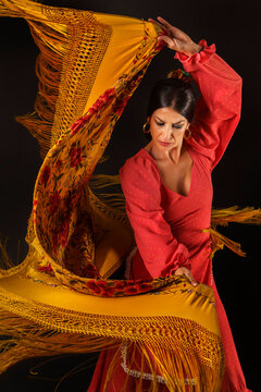 Elegant flamenco dancer showcasing traditional Spanish culture, gracefully moving embroidered manton shawl during a live performance