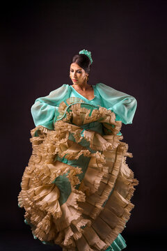 Flamenco dancer performing, wearing traditional green and beige ruffled dress, showing movement and passion