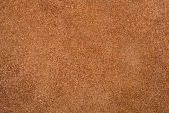A horizontal full-frame macro shot captures the uniform, fuzzy, nappy texture of a plain brown suede or nubuck leather surface