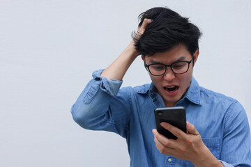 close up young asian man with stress emotion on face with during hold smartphone to reading about bad comment on social media application or read news and rumor in home for people lifestyle concept