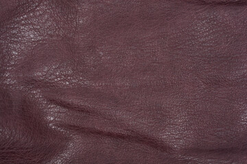 A full-frame macro shot captures the wrinkled and textured surface of dark burgundy or deep purple faux leather
