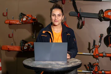 Fotobehang Cappuccino Female gardener using laptop in workshop, managing small business with power tools for landscaping and tree pruning services  © CatalnIlie