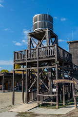 Wooden water tower stands tall in a western-style ghost town under clear blue sky in autumn season