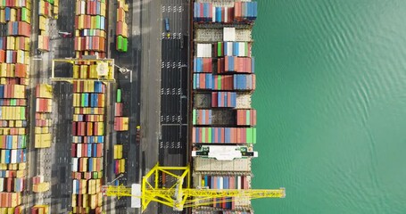 Trieste, Italy - 26 October 2025: Aerial view of a cargo ship docked at a port with shipping containers, showcasing a contrast between the colorful containers and the sea.