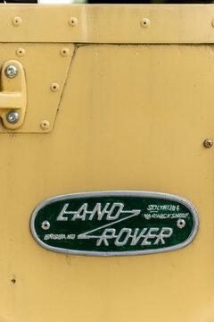 Land Rover emblem displayed on vintage yellow vehicle in a sunny outdoor setting