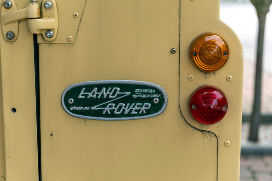 Vintage Land Rover back view showcasing iconic badge and rear lights on a sunny day in a city street