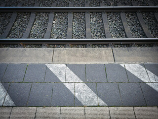 Railway tracks with ballast, adjacent asphalt, and distinctive stripe markings, platform in 27798 Hude, Lower Saxony, Germany