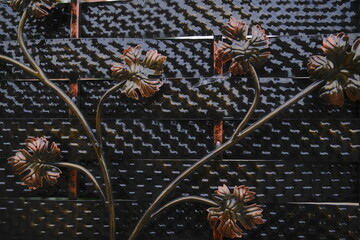 Metal leaves and vines decorate a black and bronze wrought iron fence section.