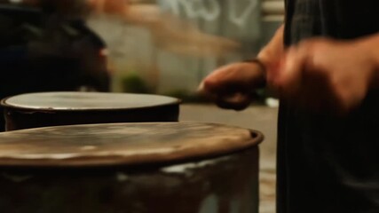 A lively street performance features rhythmic drumming by talented musicians. The atmosphere is filled with energy as people stroll by, enjoying the music in their neighborhood