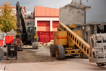 Construction site scene with mobile elevating work platform, excavator, tear down house, container, and construction site equipment.