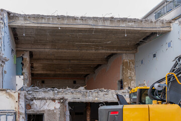 Demolition house inside, after fron wall was torn down already. Yellow excavator in front of it.