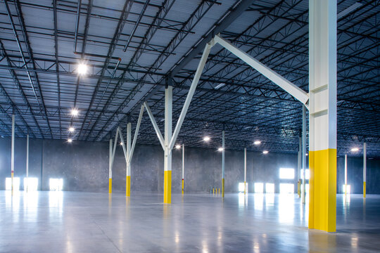 large empty warehouse featuring steel support beams - Powered by Adobe