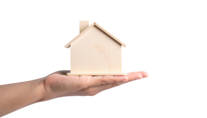 A hand holding a miniature wooden house, symbolizing home ownership, real estate, and dreams of a house