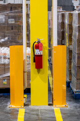 Fire extinguisher on steel column inside warehouse, fire safety
