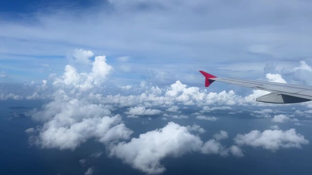 Airplane wing cruising above scattered clouds