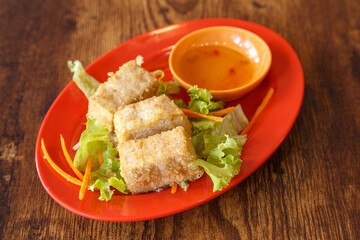 Tofu grillé – plat malaisien végétarien présenté dans une assiette colorée sur table en bois. Cubes de tofu fermes frits avec sa sauce citron. 