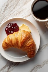 Flaky croissant with butter and berry jam on marble table