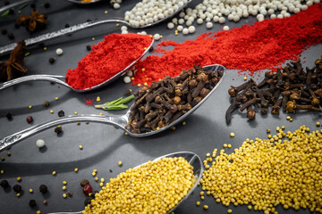 Collection of spices are spread out on a table. The spices include cumin, paprika, and turmeric
