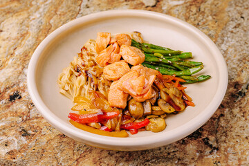 Colorful stir-fried vegetables and salmon served in a bowl on a granite surface
