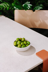 Fresh limes in a bowl on a modern table surrounded by greenery