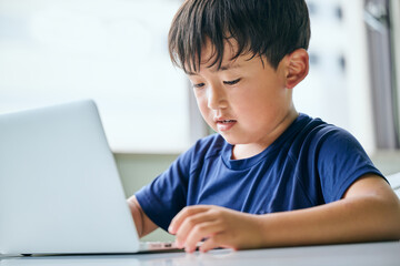 ノートパソコンでオンライン学習をする小学生の男の子