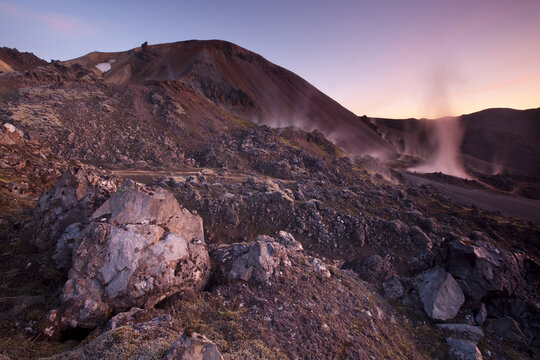View of rugged volcanic landscape with steaming vents and colorful mountains under a pastel sky, a symphony of earth and sky, Landmannalaugar, Rang&aacute;rping ytra, Iceland.