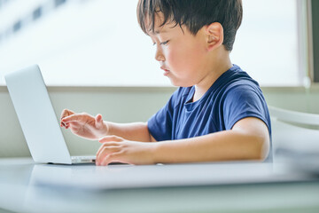 ノートパソコンでオンライン学習をする小学生の男の子