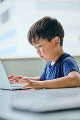 ノートパソコンでオンライン学習をする小学生の男の子