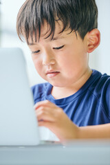 ノートパソコンでオンライン学習をする小学生の男の子