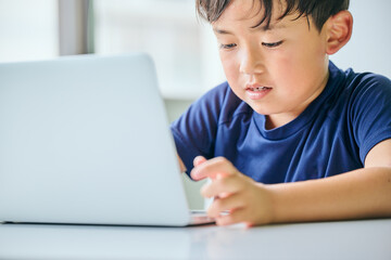 ノートパソコンでオンライン学習をする小学生の男の子