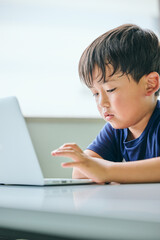 ノートパソコンでオンライン学習をする小学生の男の子