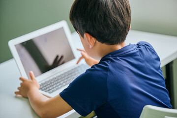 ノートパソコンでオンライン学習をする小学生の男の子