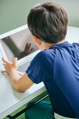 ノートパソコンでオンライン学習をする小学生の男の子