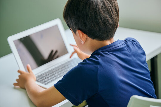 ノートパソコンでオンライン学習をする小学生の男の子