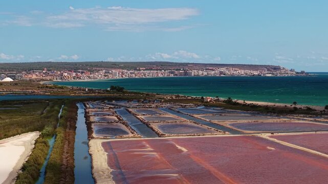 Aerial view of salt evaporation ponds near Santa Pola, Alicante, Spain. Geometric salt flats with colorful water and town by the Mediterranean Sea.