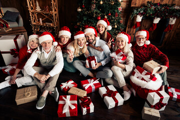 Family group celebrates Christmas together with gifts around a decorated tree in a cozy home setting