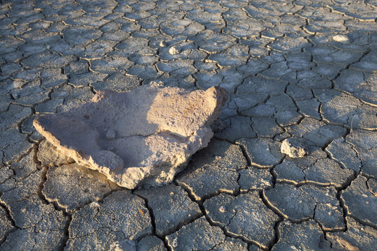 View of parched earth fractures into a mosaic of dry polygons under the sun, with a single stone resting on the cracked surface, Iceland, Iceland.